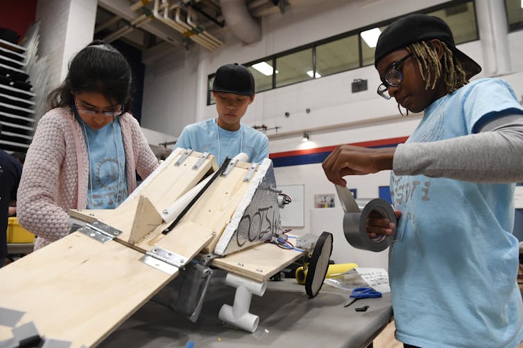 three tweens work together in a robotics competition